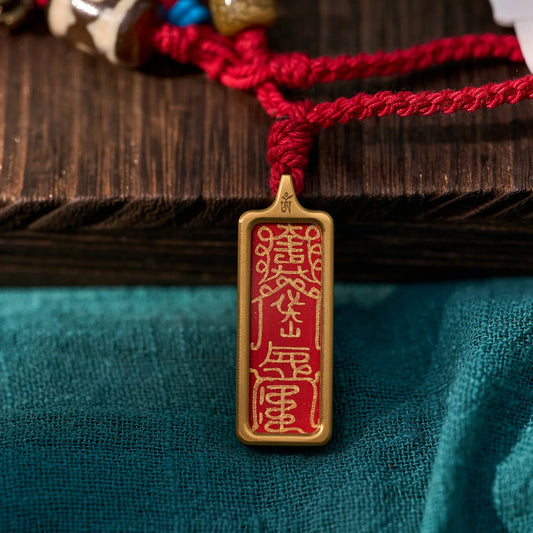 Gold and red Tibetan amulet pendant with braided red cord, spiritual jewelry on fabric